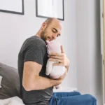 Pai amoroso segurando bebê recém-nascido em quarto aconchegante durante período de licença-paternidade